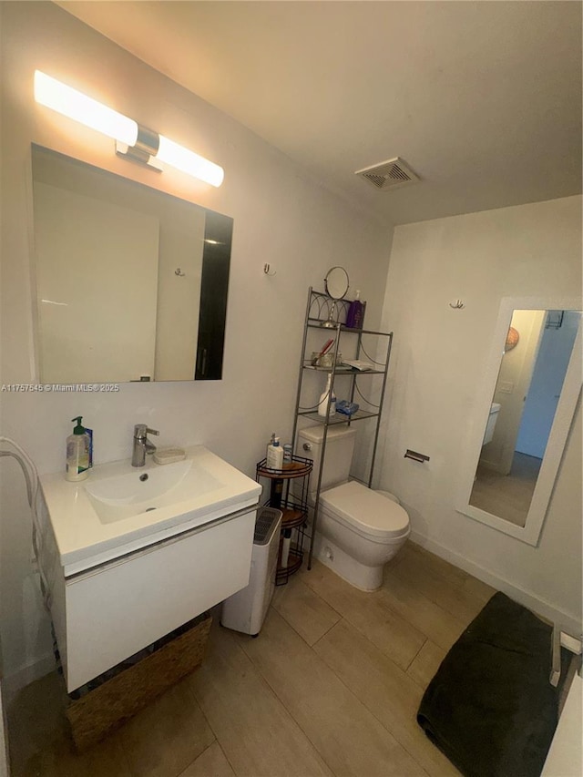 bathroom with visible vents, toilet, vanity, and wood finished floors