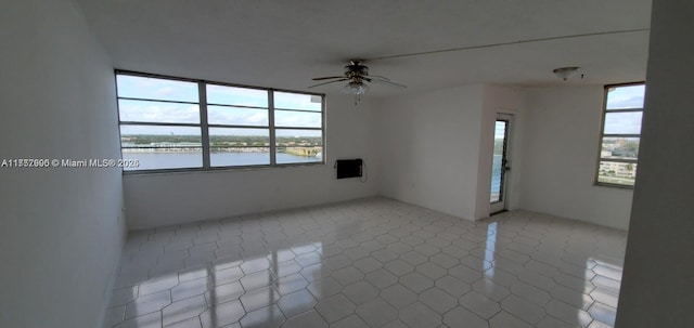 unfurnished room featuring ceiling fan and a water view