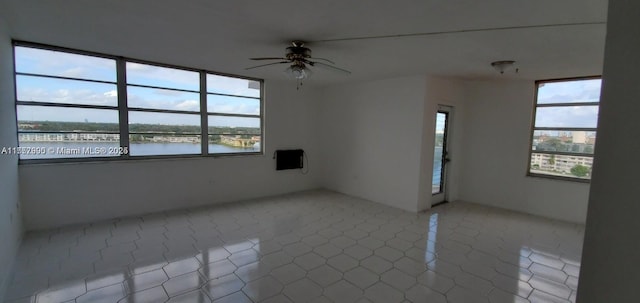 empty room featuring a wealth of natural light, a water view, and ceiling fan