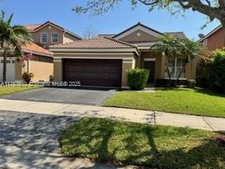 view of front of property with a front yard, a tile roof, driveway, and an attached garage