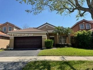 view of front of property featuring aphalt driveway, a front lawn, a tiled roof, and an attached garage