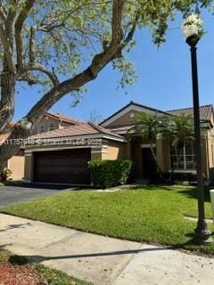 view of front of property featuring a garage, aphalt driveway, and a front yard