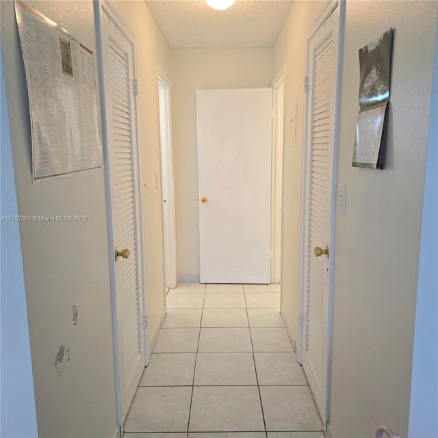 hall featuring a textured ceiling and light tile patterned flooring