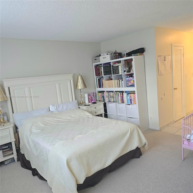 bedroom with light colored carpet and a textured ceiling