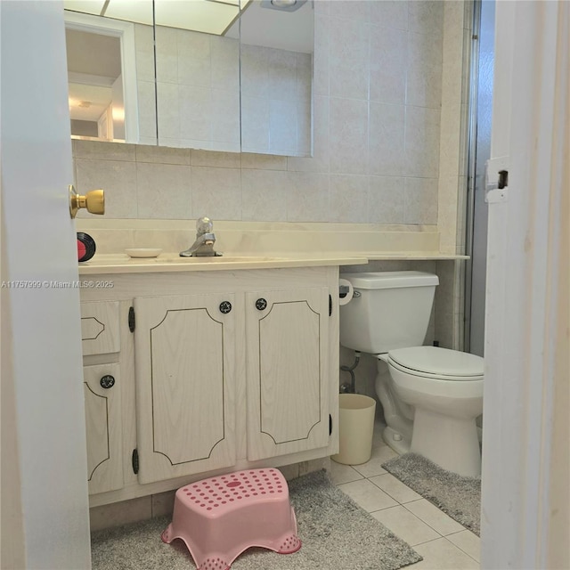 bathroom featuring toilet, vanity, tile walls, and tile patterned floors