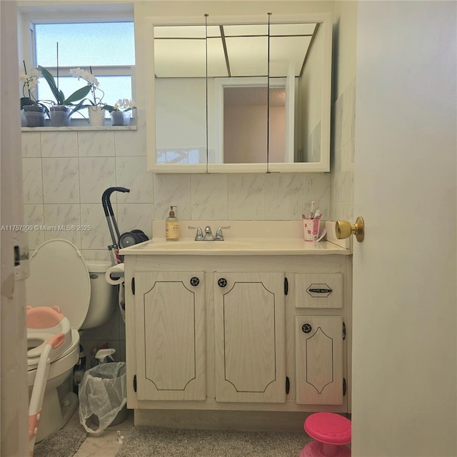 bathroom with toilet, tile walls, and vanity