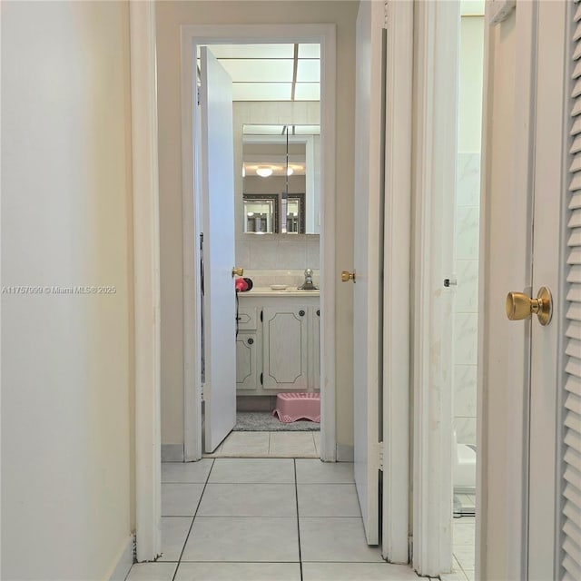 corridor featuring light tile patterned floors and a sink