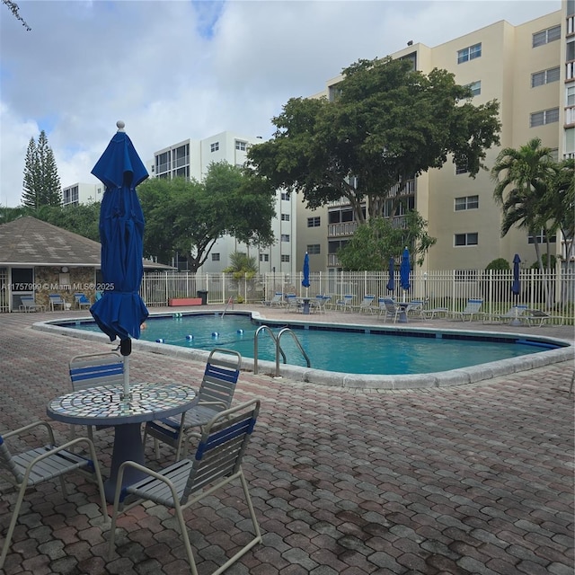 community pool with a patio area and fence