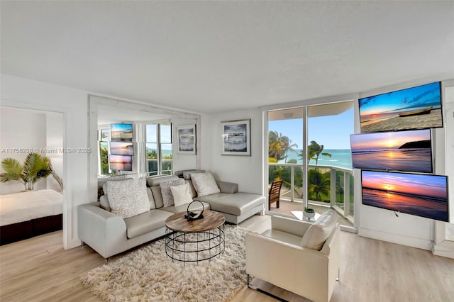 living area with plenty of natural light, floor to ceiling windows, and wood finished floors