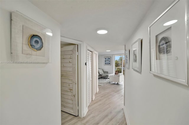 corridor featuring light wood-type flooring and baseboards