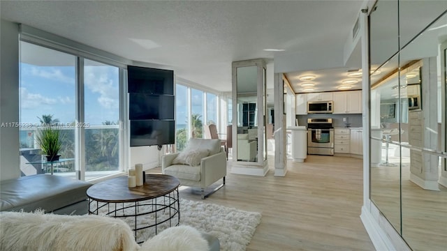 living area featuring light wood-style floors, visible vents, and a textured ceiling