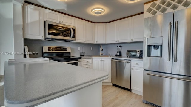 kitchen with light wood finished floors, light countertops, appliances with stainless steel finishes, and white cabinets