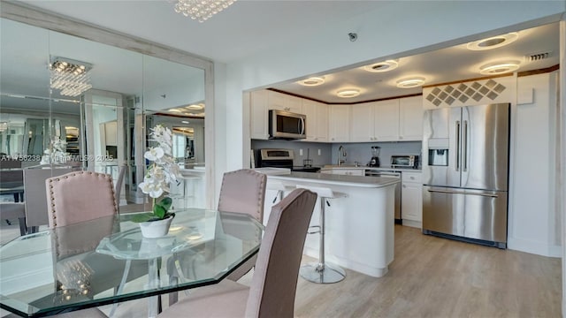 kitchen with visible vents, white cabinets, light wood-style flooring, stainless steel appliances, and light countertops