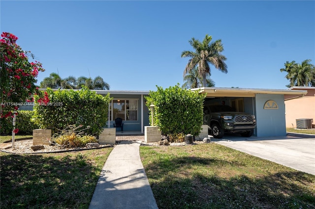 view of front of house featuring an attached carport, cooling unit, concrete driveway, stucco siding, and a front yard