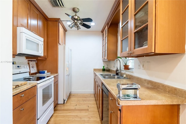 kitchen with brown cabinets, white appliances, visible vents, and a sink