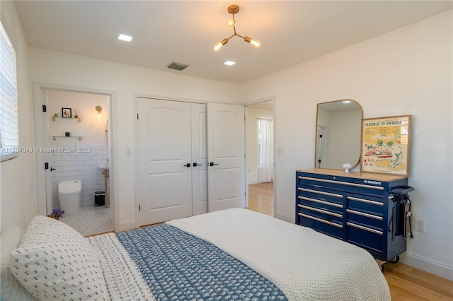 bedroom featuring baseboards, visible vents, ensuite bathroom, light wood-type flooring, and a closet