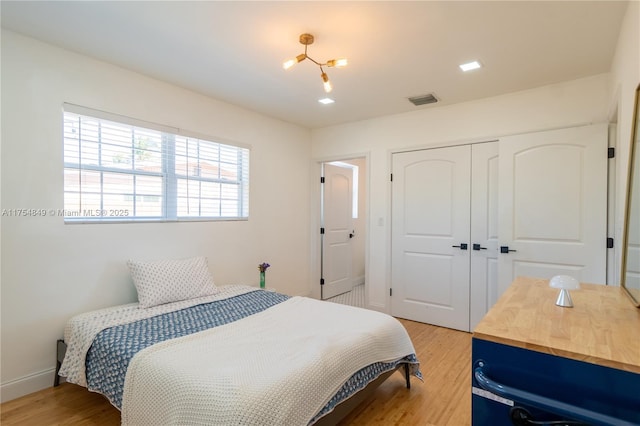 bedroom with baseboards, a closet, visible vents, and light wood-style floors