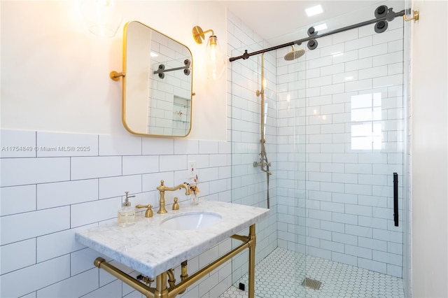 bathroom featuring a stall shower, a sink, and tile walls