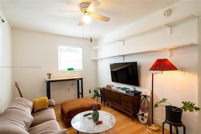 living area featuring ceiling fan, wood finished floors, and baseboards