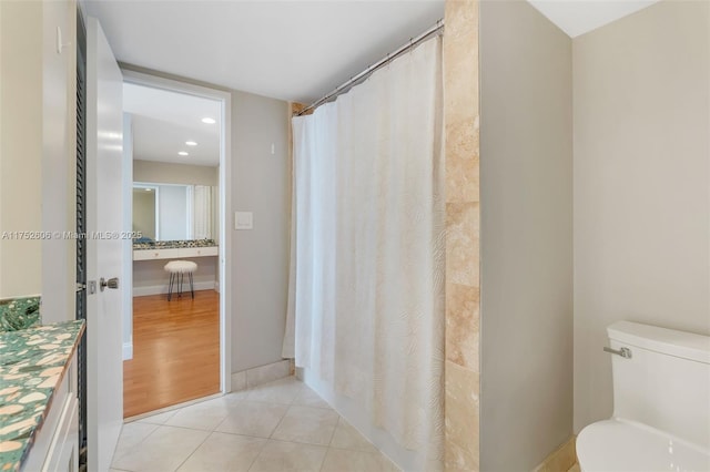 bathroom with a shower with shower curtain, toilet, vanity, tile patterned flooring, and baseboards