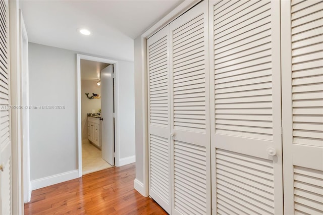 corridor featuring recessed lighting, baseboards, and light wood finished floors