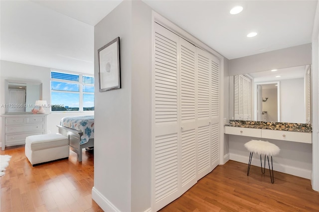 corridor with recessed lighting, wood finished floors, and baseboards