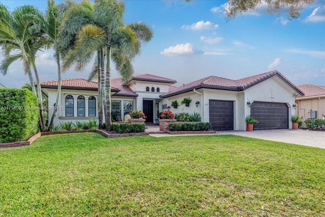 mediterranean / spanish-style home with a garage, a tile roof, decorative driveway, a front yard, and stucco siding