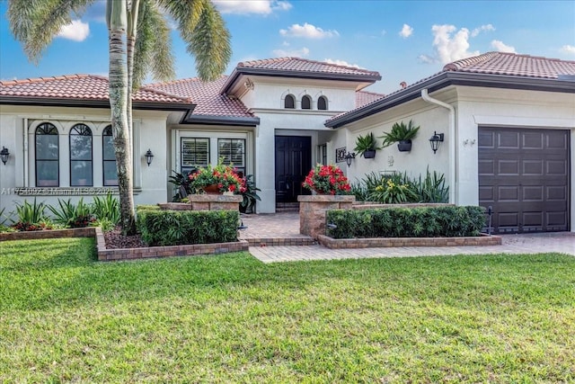 mediterranean / spanish home with an attached garage, stucco siding, a tiled roof, and a front yard