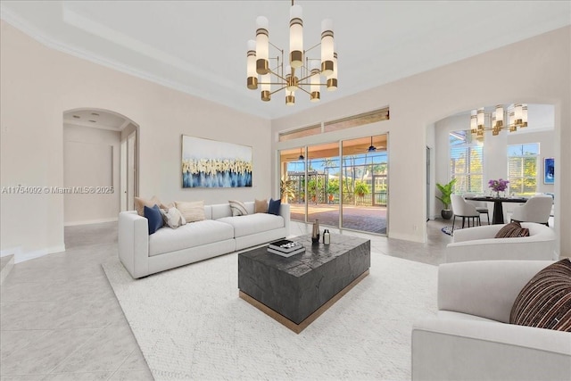 living room featuring crown molding, arched walkways, a notable chandelier, and baseboards