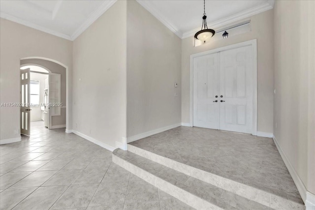 entryway featuring baseboards, arched walkways, crown molding, and light tile patterned flooring