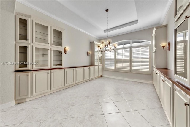 empty room with ornamental molding, a raised ceiling, light tile patterned floors, and an inviting chandelier