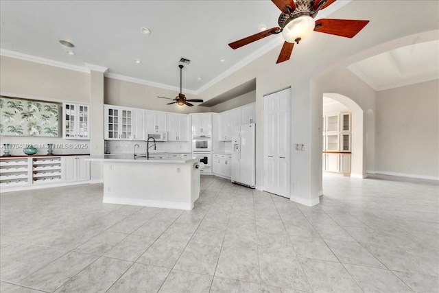 kitchen featuring white appliances, arched walkways, crown molding, and light tile patterned flooring