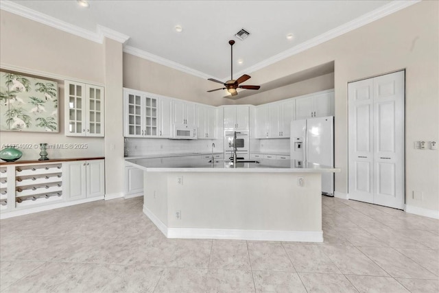 kitchen with white appliances, ceiling fan, a kitchen island with sink, and white cabinetry