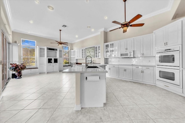 kitchen featuring white appliances, tasteful backsplash, ornamental molding, light countertops, and a sink