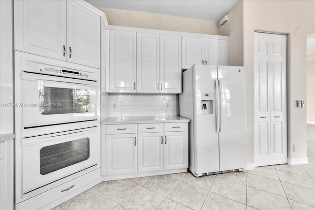 kitchen with white appliances, white cabinetry, light countertops, and decorative backsplash