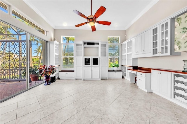 unfurnished sunroom with ceiling fan and built in desk