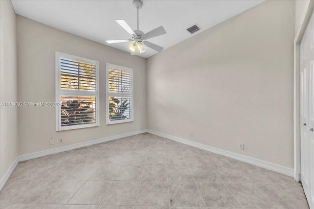 empty room featuring lofted ceiling, visible vents, ceiling fan, and baseboards