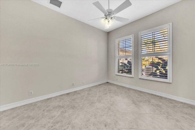 spare room with a ceiling fan, tile patterned flooring, visible vents, and baseboards