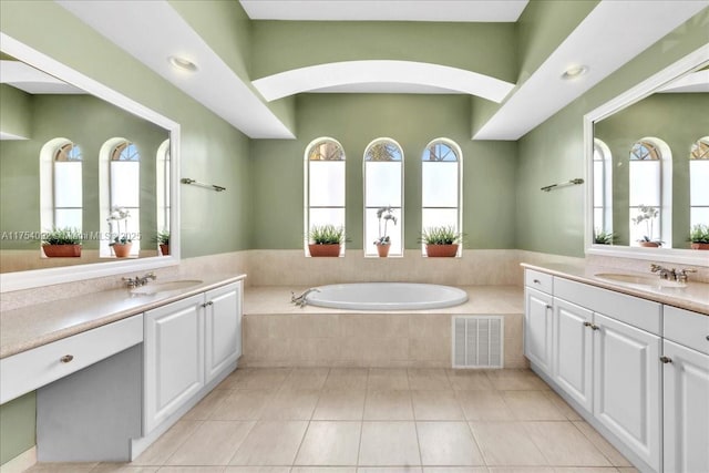 full bathroom with two vanities, visible vents, a sink, and a bath