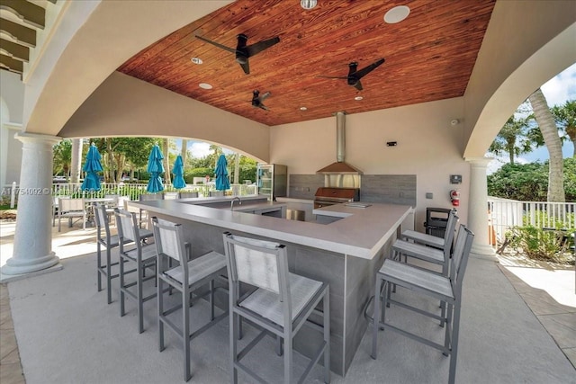 view of patio with outdoor wet bar, fence, an outdoor kitchen, and ceiling fan