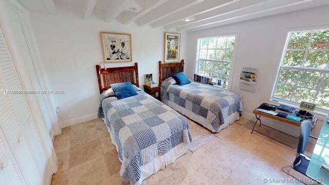 bedroom featuring multiple windows, baseboards, and beamed ceiling