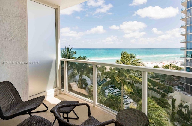 balcony with a water view and a view of the beach