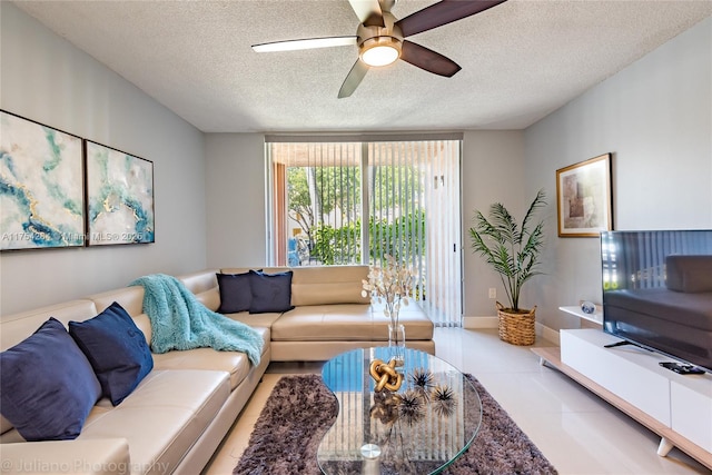 living area featuring tile patterned flooring, baseboards, ceiling fan, and a textured ceiling