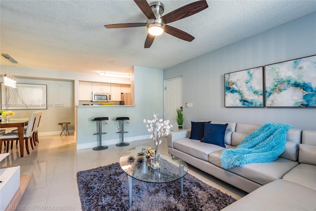 living area featuring a textured ceiling, light tile patterned flooring, and baseboards