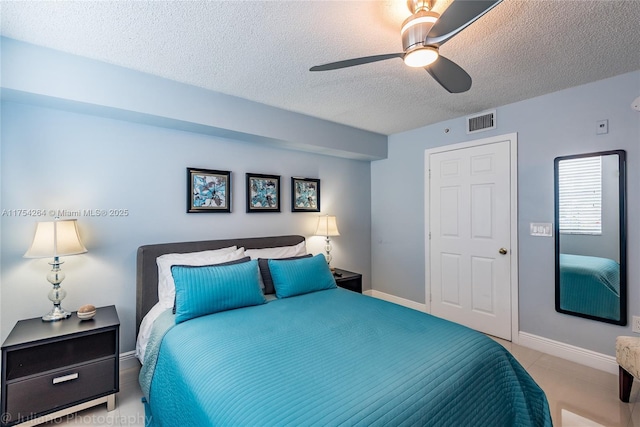 bedroom with a textured ceiling, baseboards, visible vents, and a ceiling fan