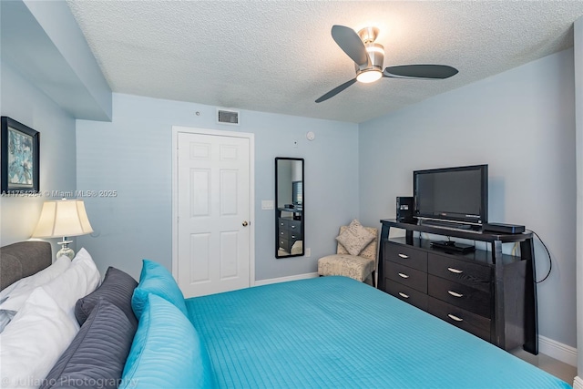 bedroom with a ceiling fan, baseboards, visible vents, and a textured ceiling