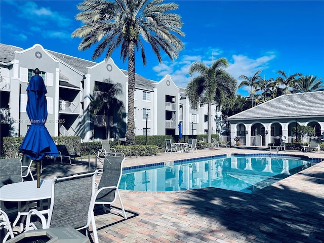 community pool with a patio and fence