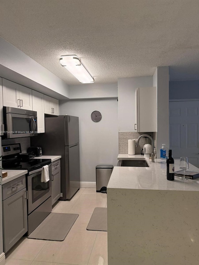 kitchen featuring stainless steel appliances, a sink, decorative backsplash, and light tile patterned floors