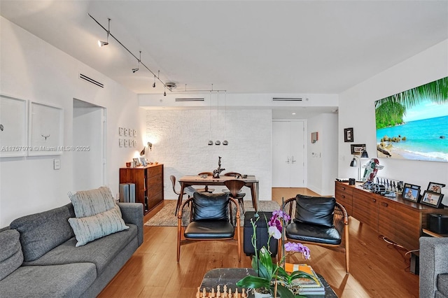 living area with track lighting, visible vents, and wood finished floors