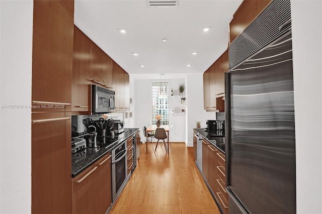 kitchen with light wood finished floors, visible vents, modern cabinets, and appliances with stainless steel finishes